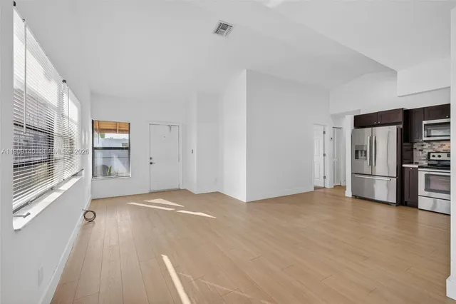 a view of empty room with wooden floor and window