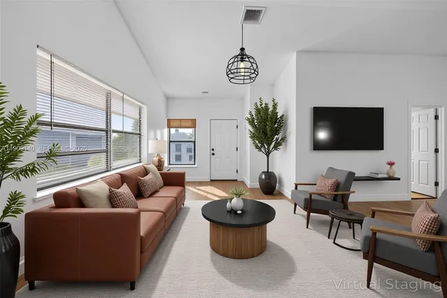 a living room with furniture potted plant and a flat screen tv