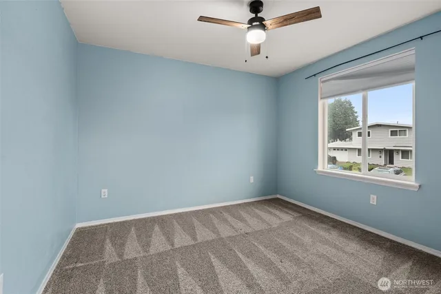 an empty room with a window and a fan