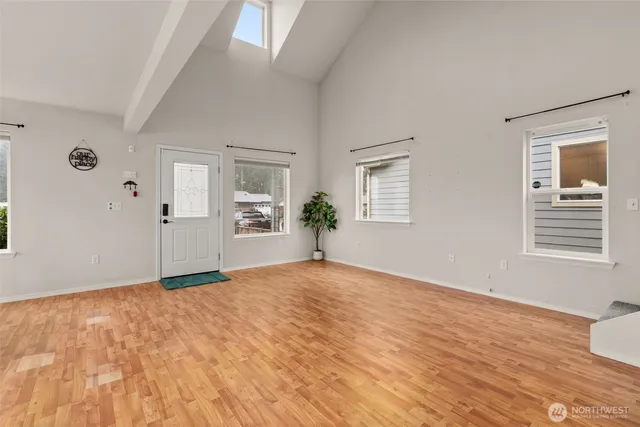a view of an empty room with window and wooden floor
