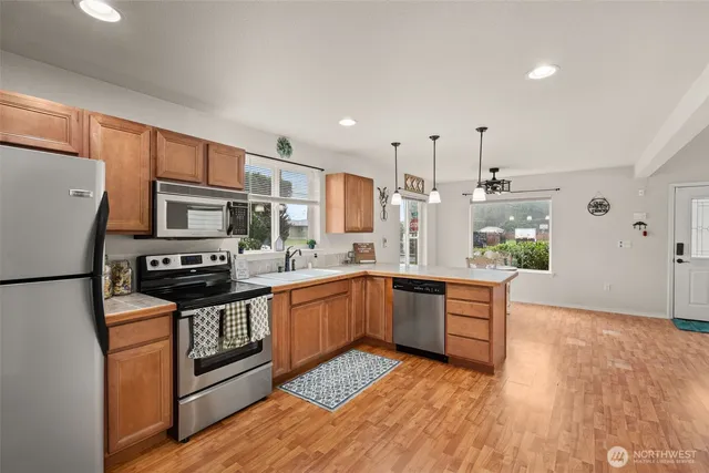 a kitchen with stainless steel appliances granite countertop a refrigerator a stove top oven a sink dishwasher and wooden floor