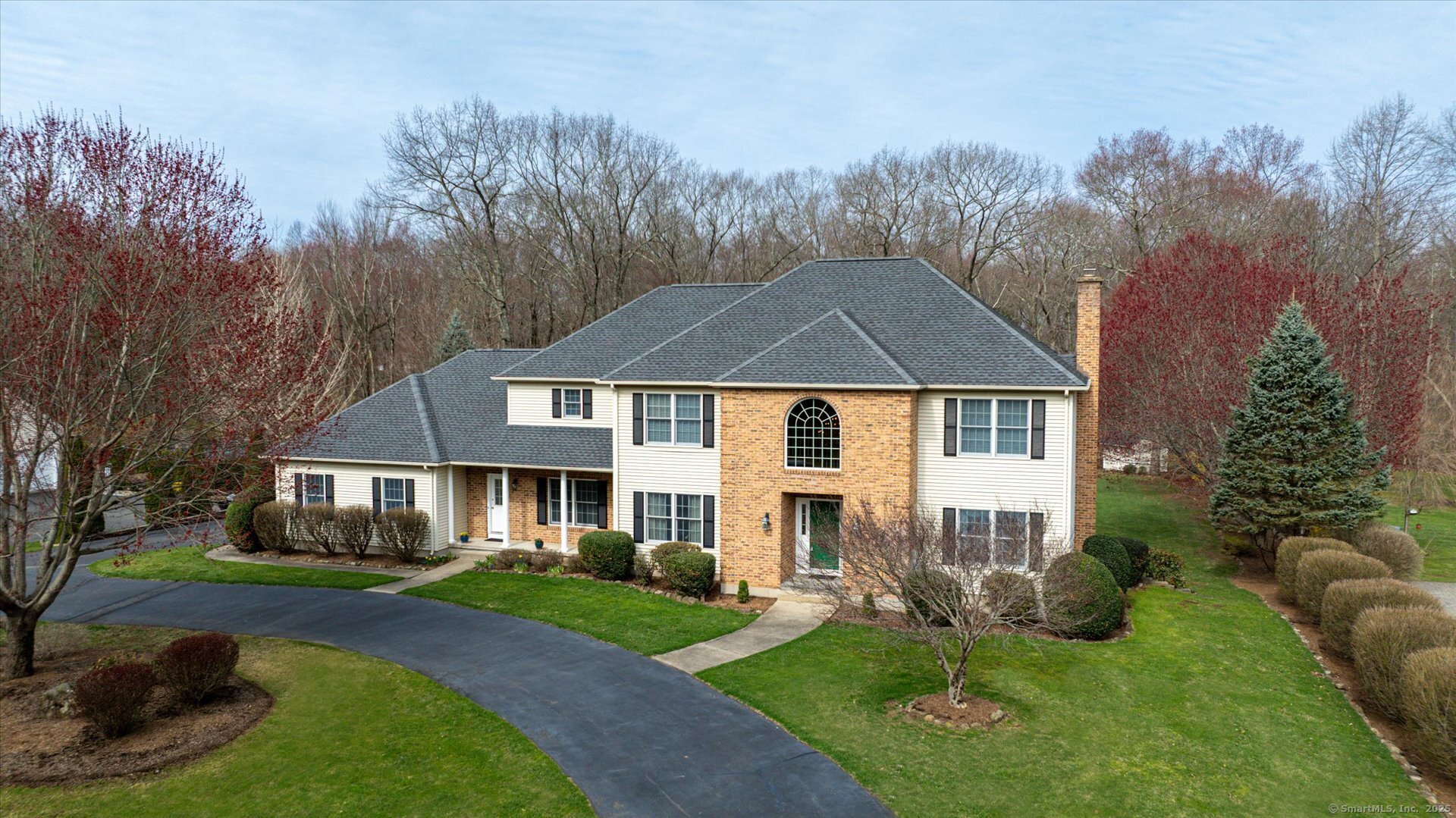 a view of a white house with a yard plants and large tree
