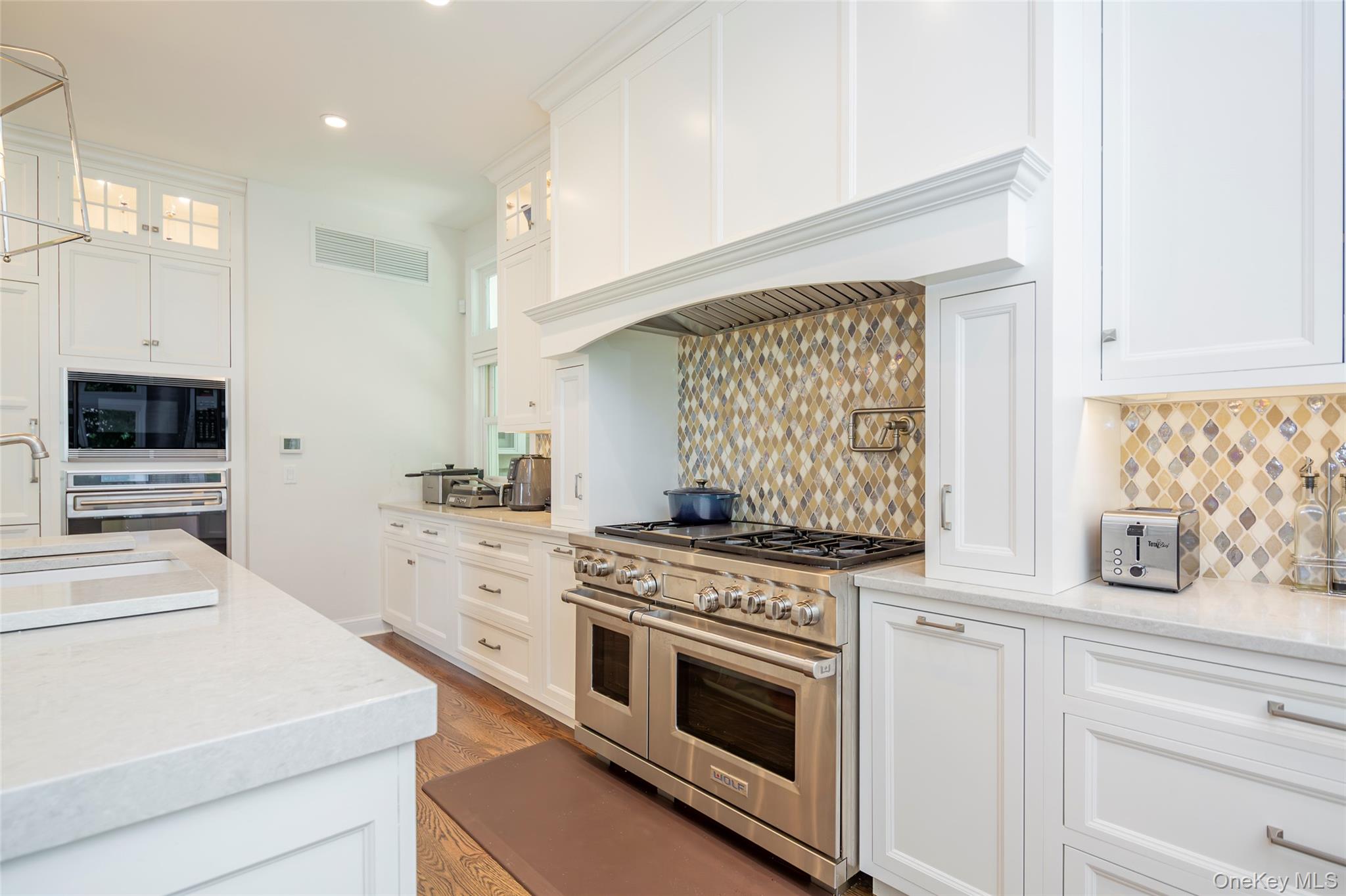 652 Noyac Path Water Mill, NY 11976 - Photo 14 of 41 Kitchen with white cabinets, visible vents, stainless steel appliances, glass insert cabinets, and light wood-type flooring