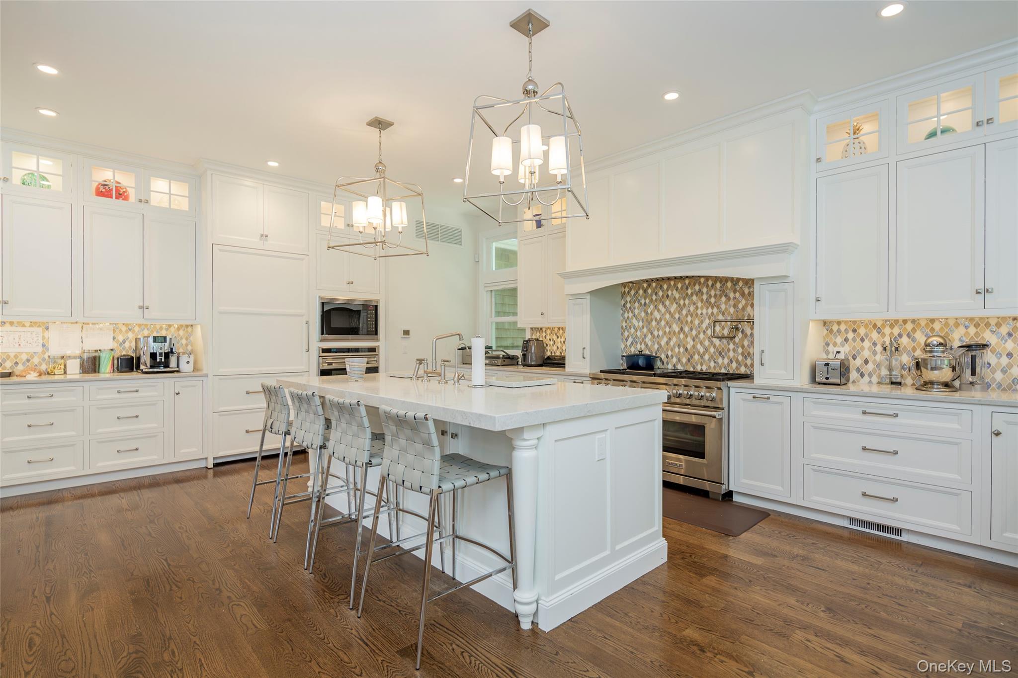 652 Noyac Path Water Mill, NY 11976 - Photo 15 of 41 Kitchen with white cabinetry, light countertops, a chandelier, dark wood finished floors, and appliances with stainless steel finishes