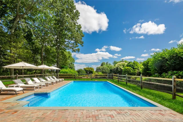 a view of a swimming pool with lawn chairs under an umbrella