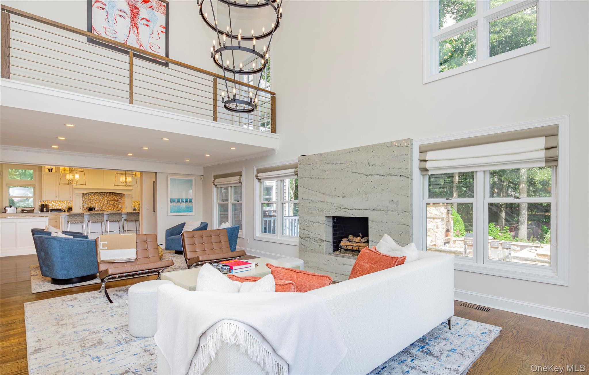 652 Noyac Path Water Mill, NY 11976 - Photo 7 of 41 Living room featuring baseboards, a towering ceiling, a high end fireplace, a notable chandelier, and wood finished floors