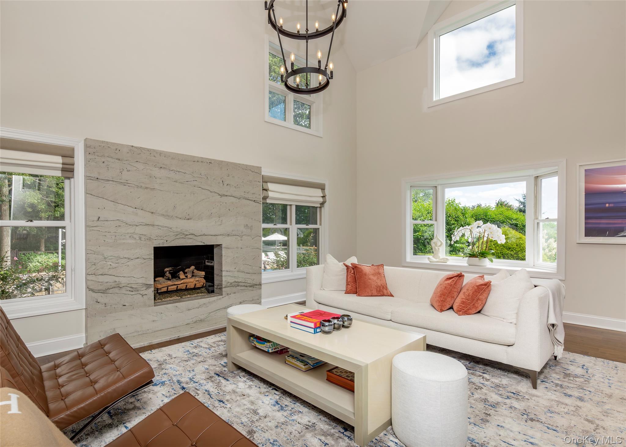 652 Noyac Path Water Mill, NY 11976 - Photo 8 of 41 Living room with a notable chandelier, a fireplace, a high ceiling, wood finished floors, and baseboards