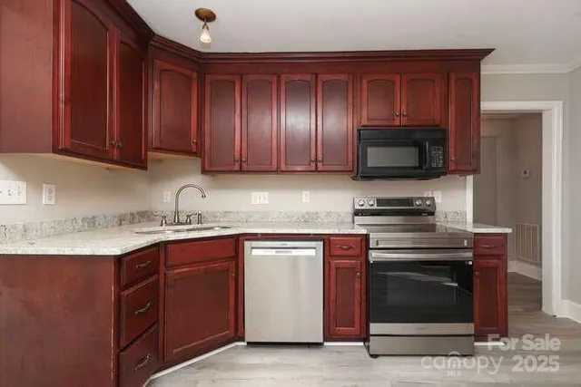 a kitchen with stainless steel appliances granite countertop wooden cabinets a stove and a sink