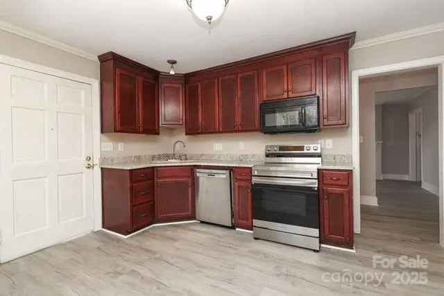 a kitchen with granite countertop wooden cabinets stainless steel appliances and a window