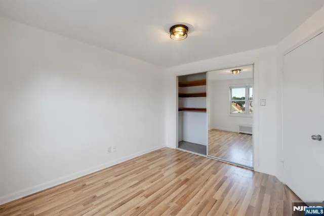 an empty room with wooden floor and kitchen