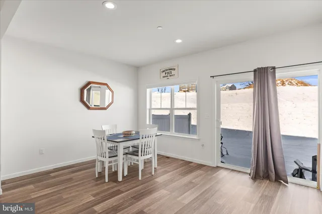 a dining room with wooden floor a glass table and chairs