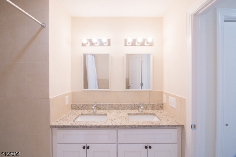 1664 Stuyvesant Avenue, Unit 306 Union, NJ 07083 - Photo 16 of 22 a bathroom with a granite countertop sink and a mirror
