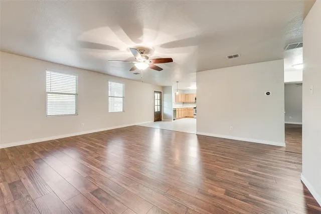 a view of an empty room with a window and wooden floor