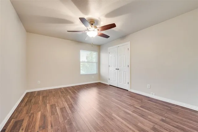 a view of an empty room with a window and wooden floor