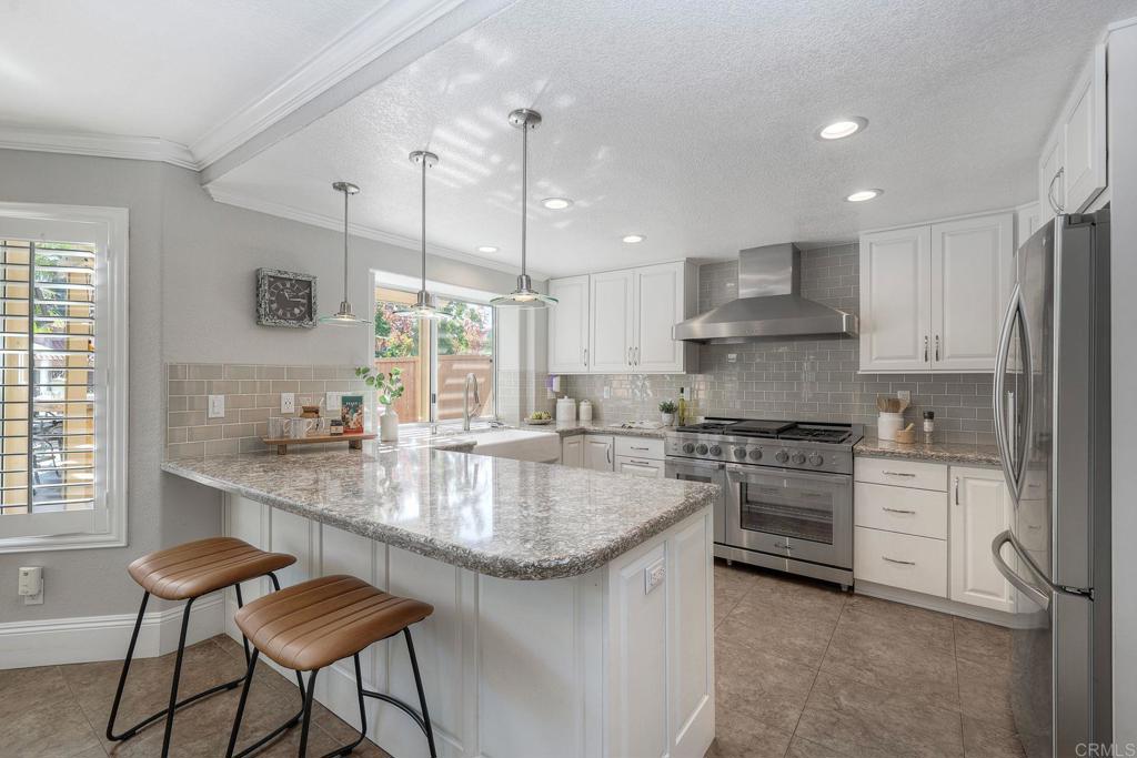 13979 Hickory Street Poway, CA 92064 - Photo 3 of 37 a kitchen with stainless steel appliances granite countertop a stove a sink a oven a dining table and chairs with wooden floor