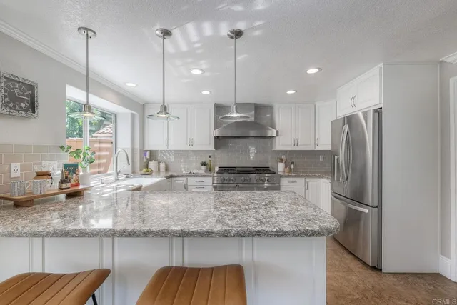 a kitchen with stainless steel appliances granite countertop a refrigerator a sink and a stove