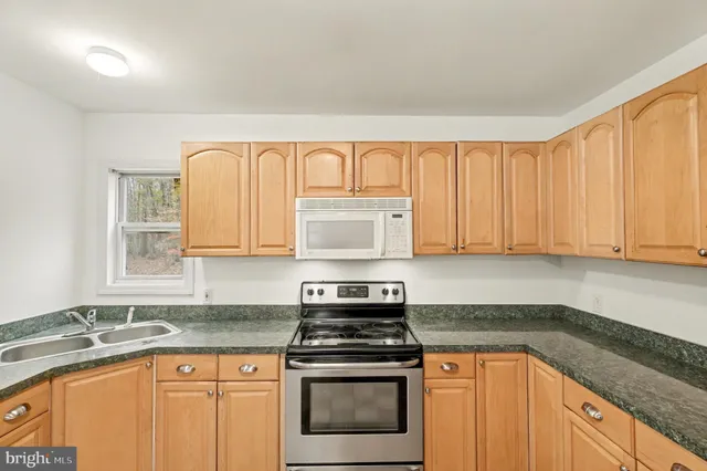 a kitchen with granite countertop a stove sink and cabinets
