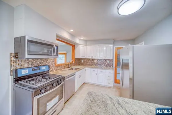 a kitchen with granite countertop a sink a stove and cabinets