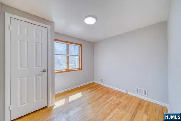 a view of an empty room with a window and wooden floor