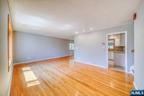 a view of an empty room with window and wooden floor