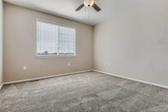 an empty room with a window and a fan