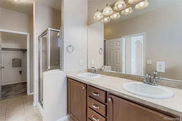 a bathroom with a sink double vanity granite and a shower