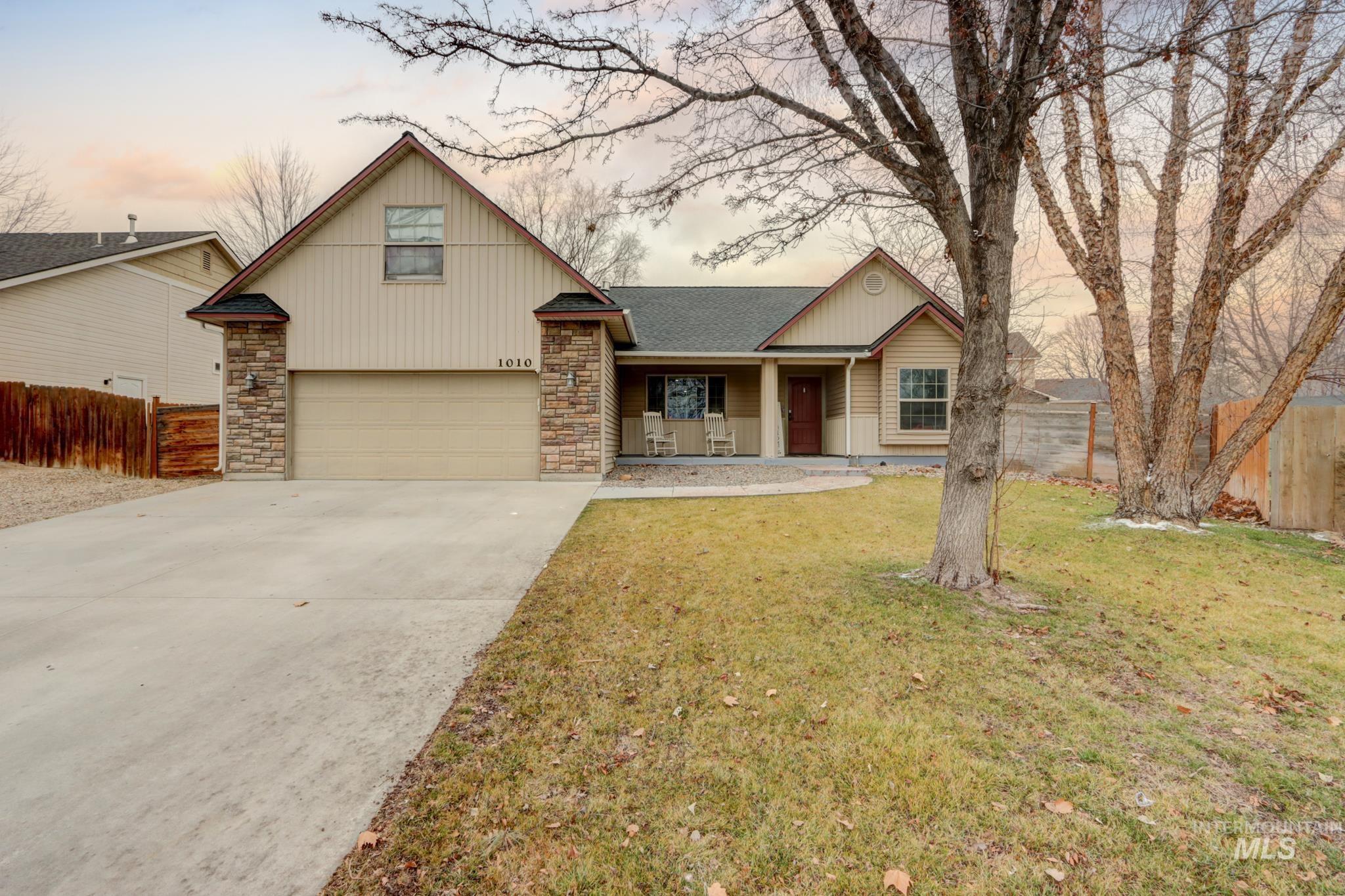 1010 North Rodeo Street Parma, ID 83660 - Photo 1 of 1 View of front facade with a porch, concrete driveway, a garage, stone siding, and a shingled roof