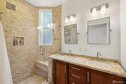 a bathroom with a granite countertop sink a mirror and shower