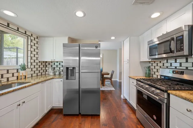 a kitchen with stainless steel appliances granite countertop a refrigerator stove and sink