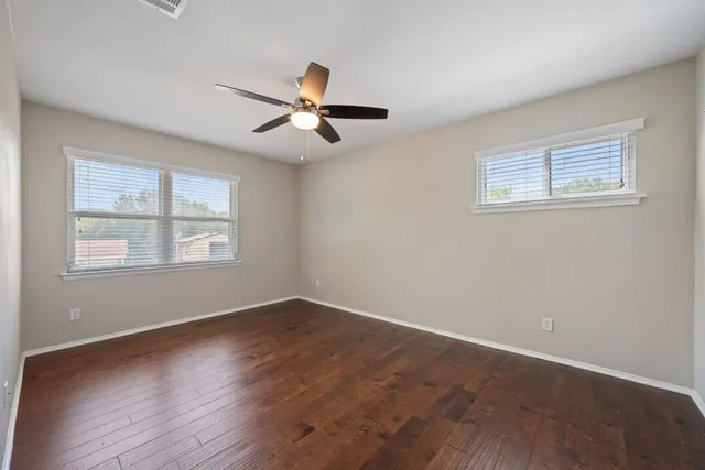 a view of empty room with wooden floor and fan