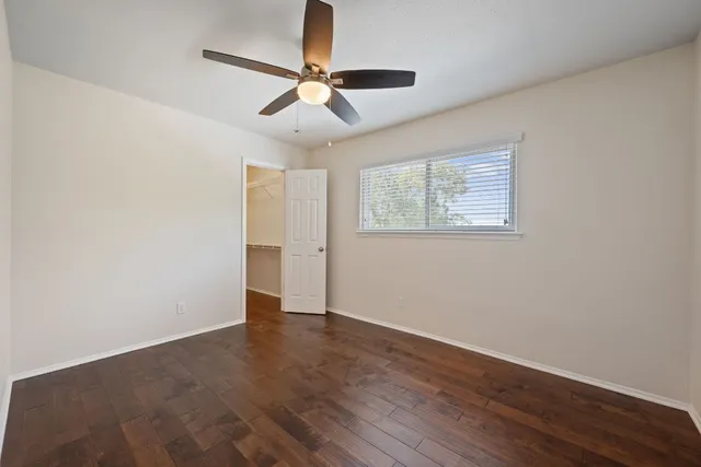 a view of empty room with wooden floor and fan