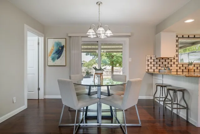 a dining room with wooden floor a chandelier a glass table and chairs