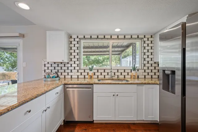 a kitchen with stainless steel appliances granite countertop a sink and cabinets