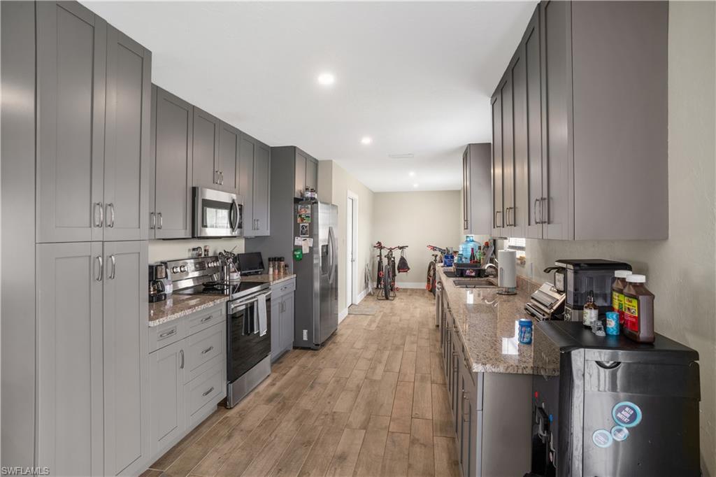 4500 30th Place Southwest Naples, FL 34116 - Photo 8 of 15 a kitchen with stainless steel appliances granite countertop a stove top oven a refrigerator a sink and dishwasher with wooden floor