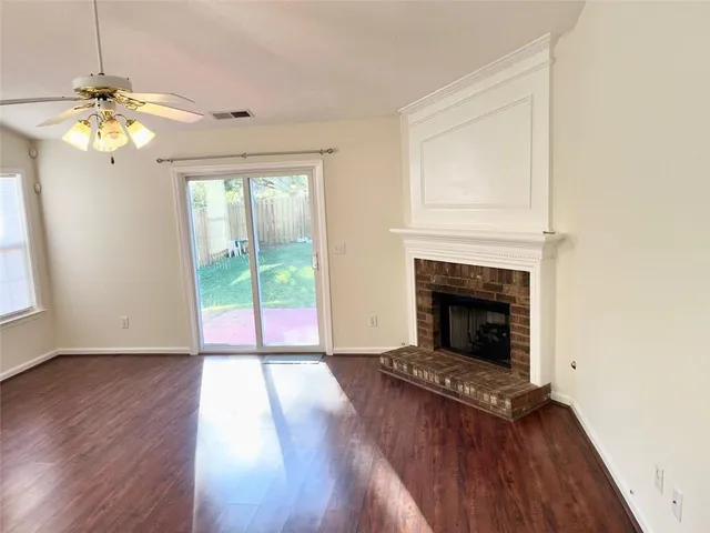 an empty room with a window and chandelier fan