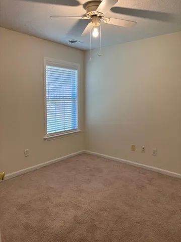 an empty room with a window and a fan