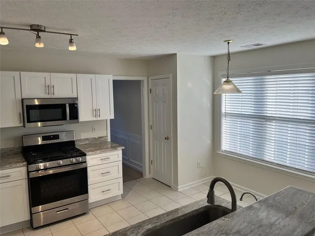 an empty room with wooden floor chandelier and windows