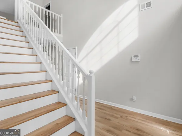 a view of staircase with wooden floor and white walls