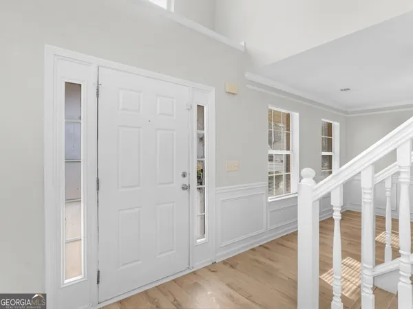 a view of front door with white walls and stairs