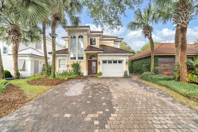 a view of a white house with a yard and palm trees