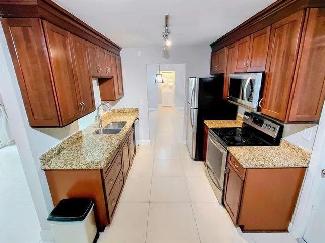 a kitchen with stainless steel appliances granite countertop wooden cabinets a stove top oven a sink and dishwasher
