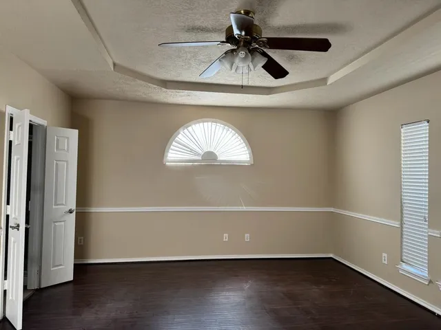 an empty room with wooden floor cabinet and windows