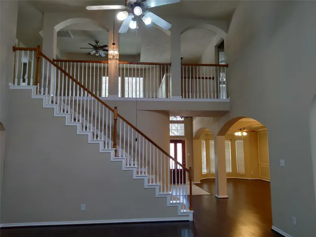 a view of staircase with wooden floor and fan