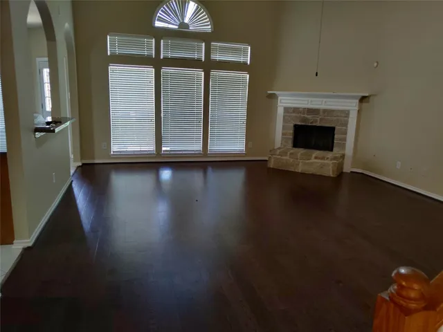an empty room with wooden floor fireplace and windows