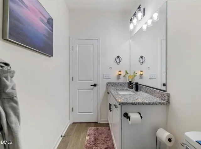 a bathroom with a granite countertop sink a toilet and mirror