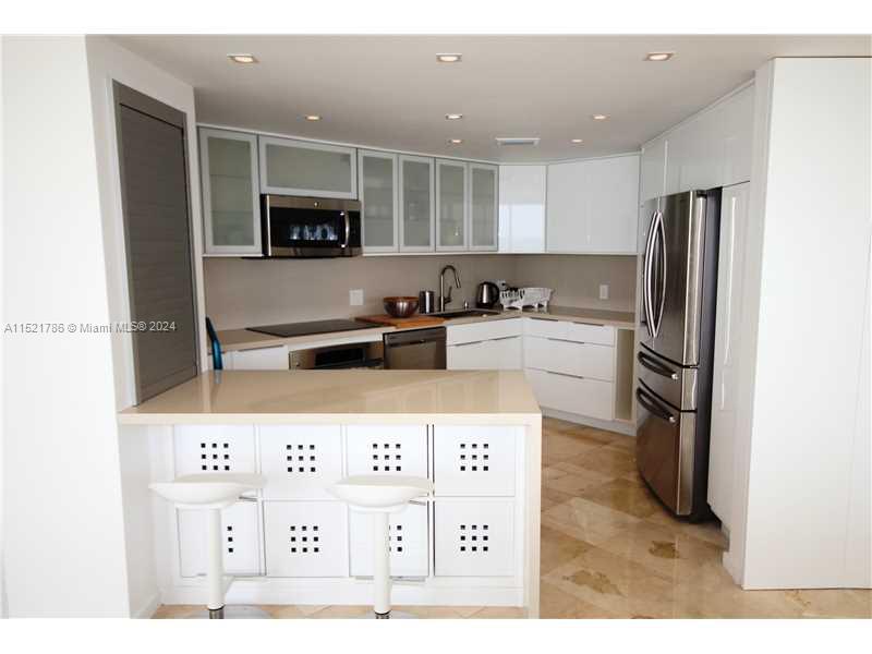 5151 Collins Avenue, Unit 532 Miami Beach, FL 33140 - Photo 12 of 62 a kitchen with stainless steel appliances kitchen island granite countertop a refrigerator and a sink
