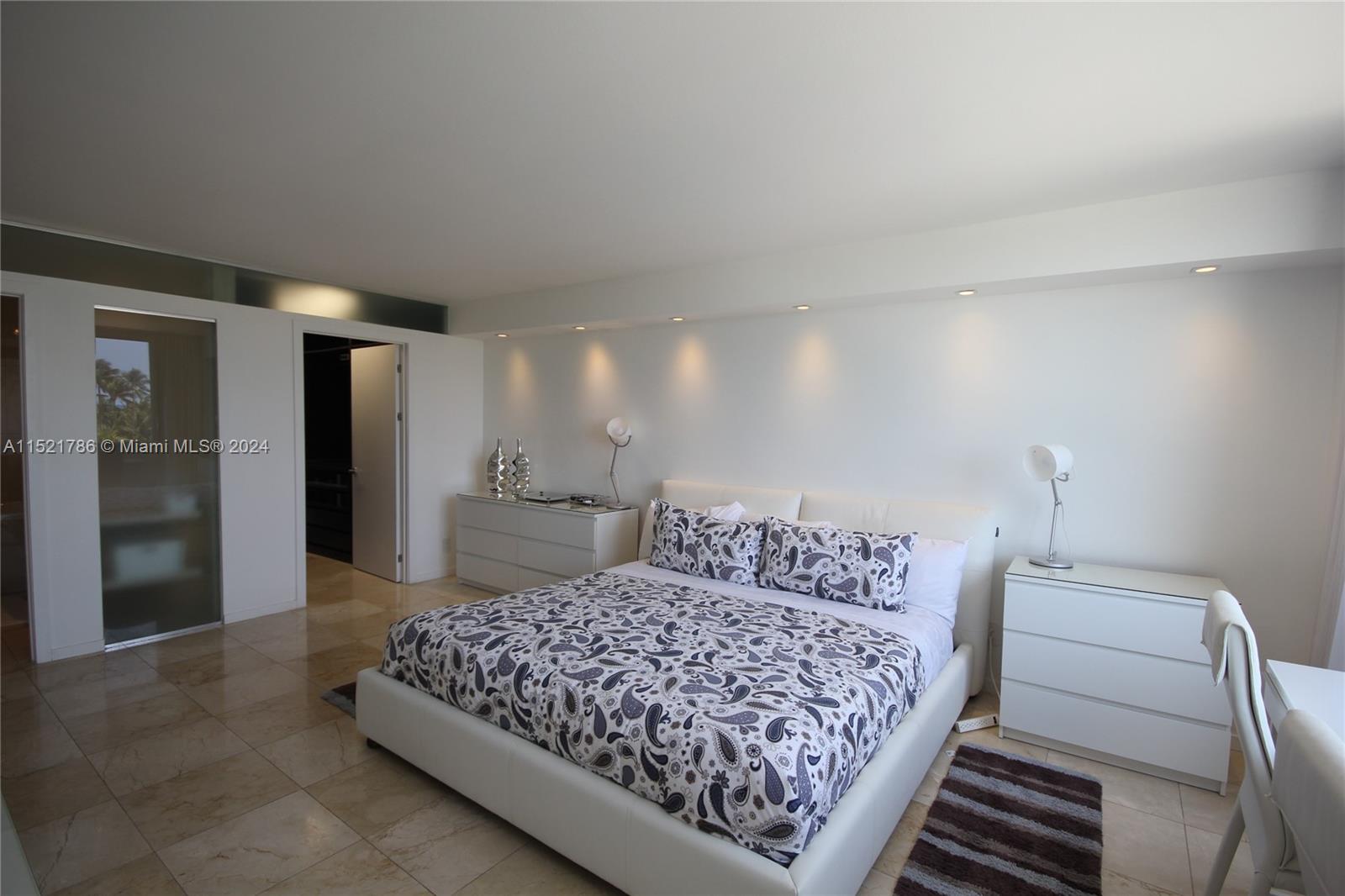 5151 Collins Avenue, Unit 532 Miami Beach, FL 33140 - Photo 17 of 62 a bedroom with a large bed and a chandelier