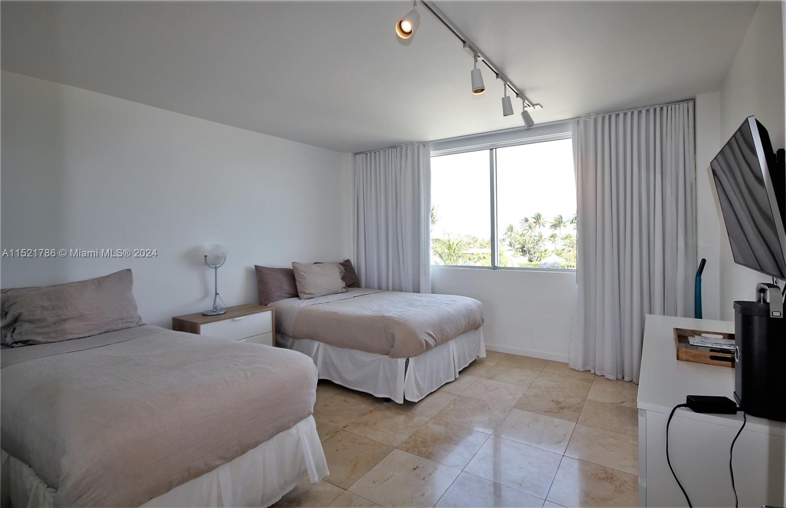 5151 Collins Avenue, Unit 532 Miami Beach, FL 33140 - Photo 26 of 62 a bedroom with two beds and a flat screen television