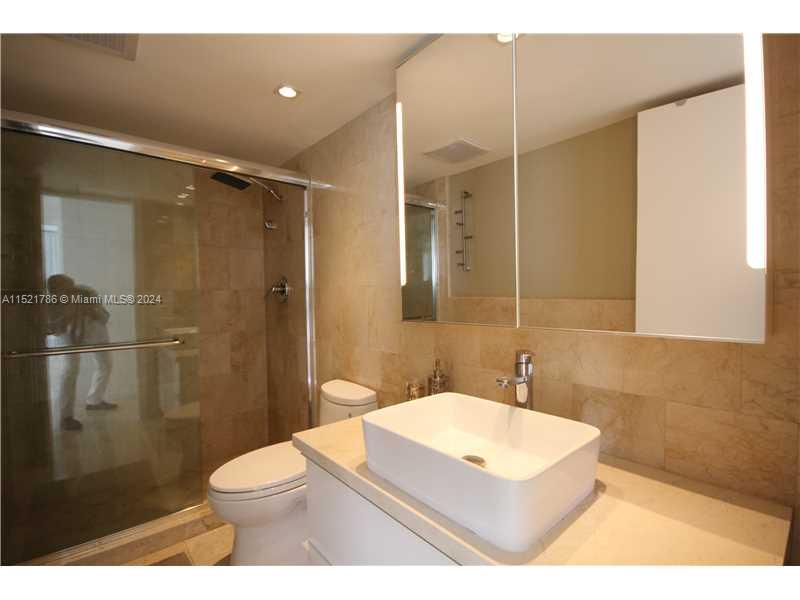 5151 Collins Avenue, Unit 532 Miami Beach, FL 33140 - Photo 29 of 62 a bathroom with a sink a toilet a shower and a mirror