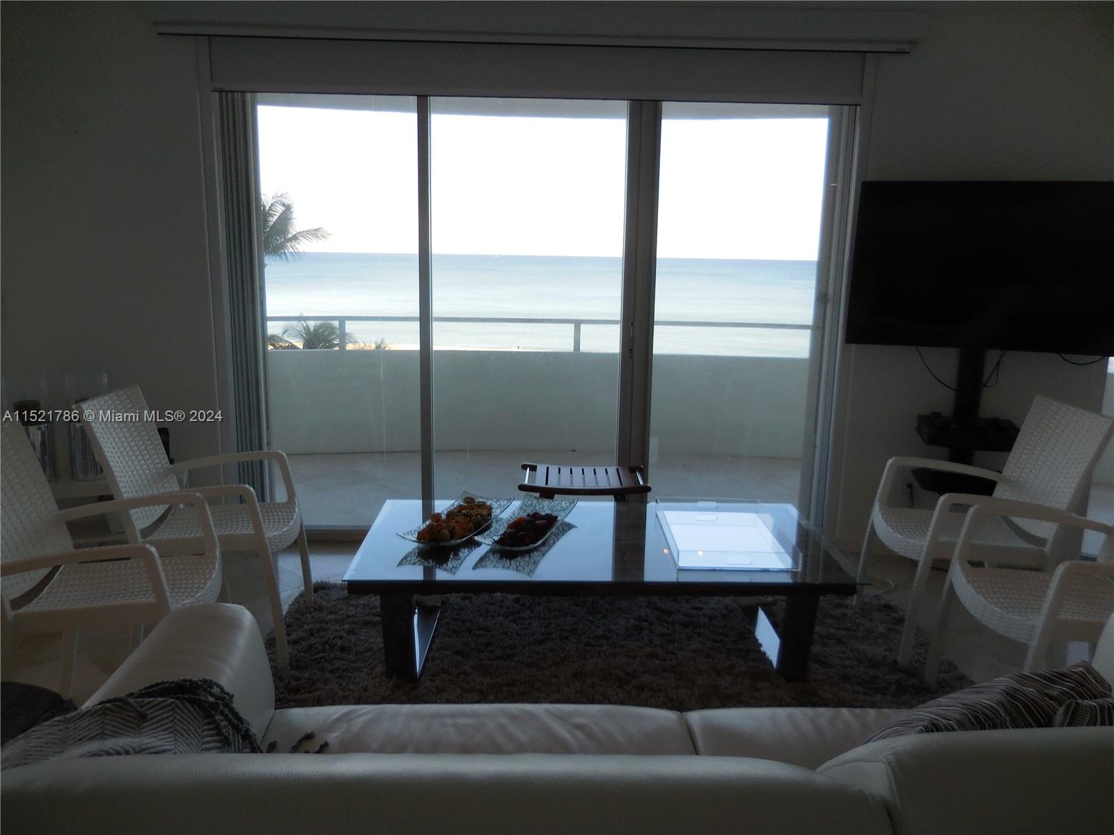 5151 Collins Avenue, Unit 532 Miami Beach, FL 33140 - Photo 56 of 62 a living room with a couch and a floor to ceiling window